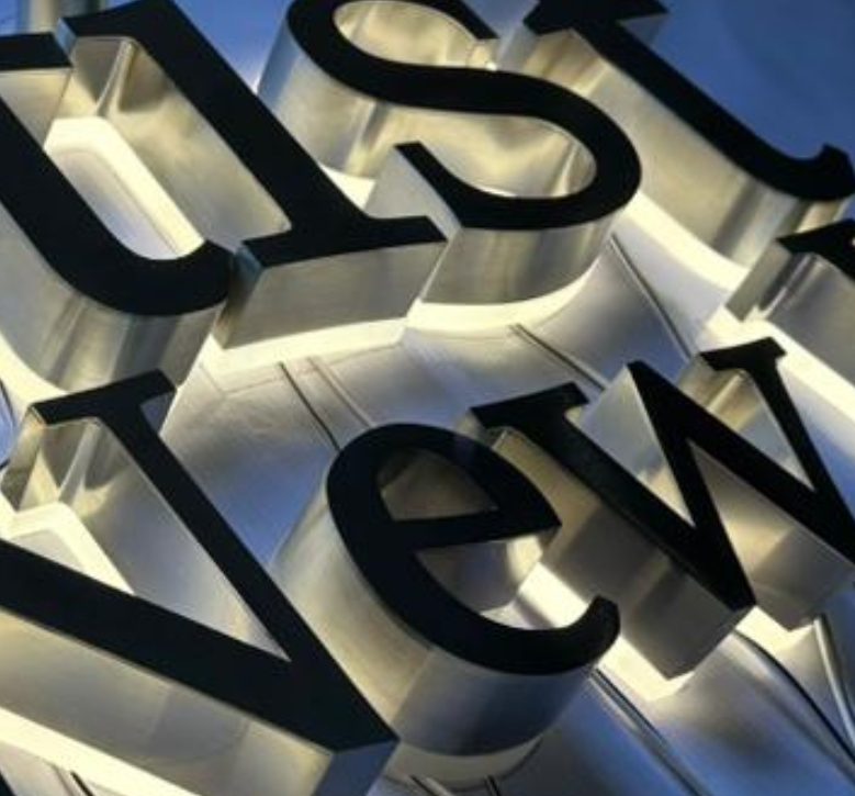 Backlit stainless steel channel letters and logo on a dark feature wall in Vancouver