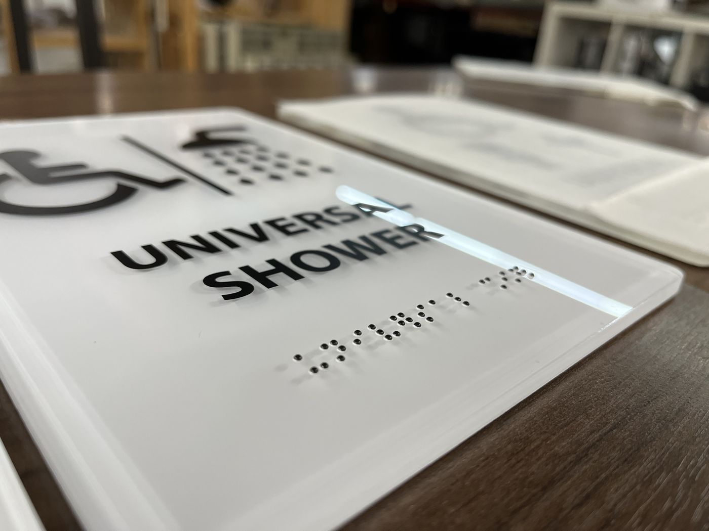 Close-up of a universal shower sign with raised braille lettering