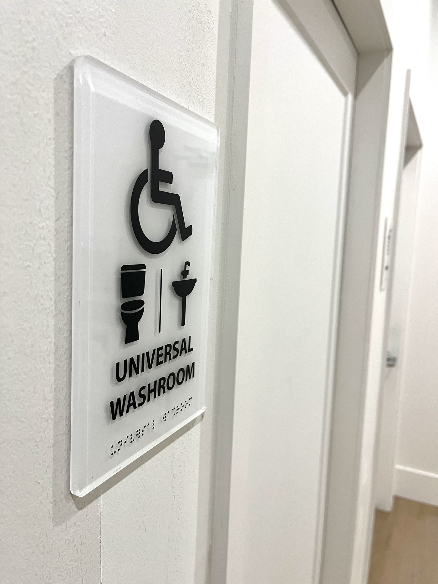 Accessible universal washroom sign with tactile braille in Vancouver